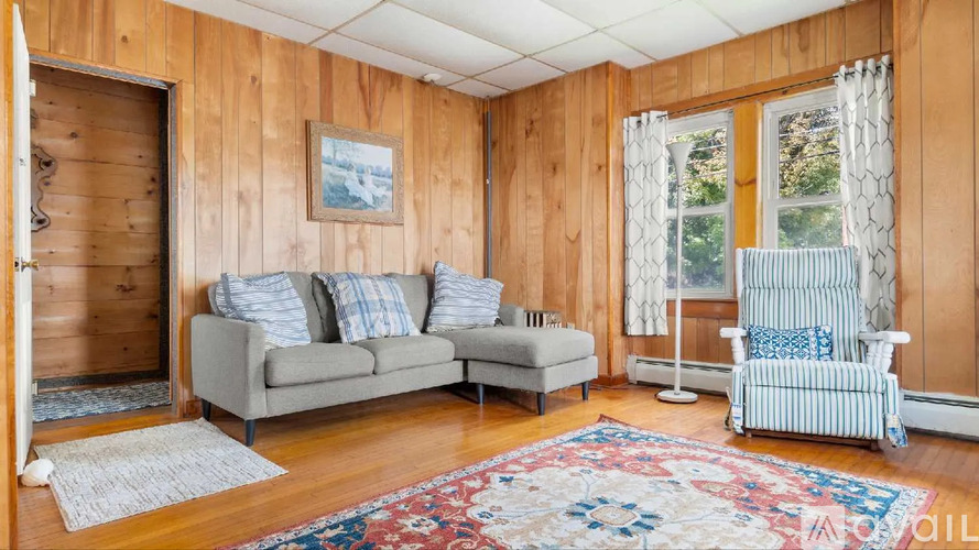 A living room with a grey couch, a chair, and a rug.