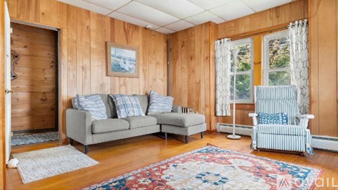 A living room with a grey couch, a chair, and a rug.