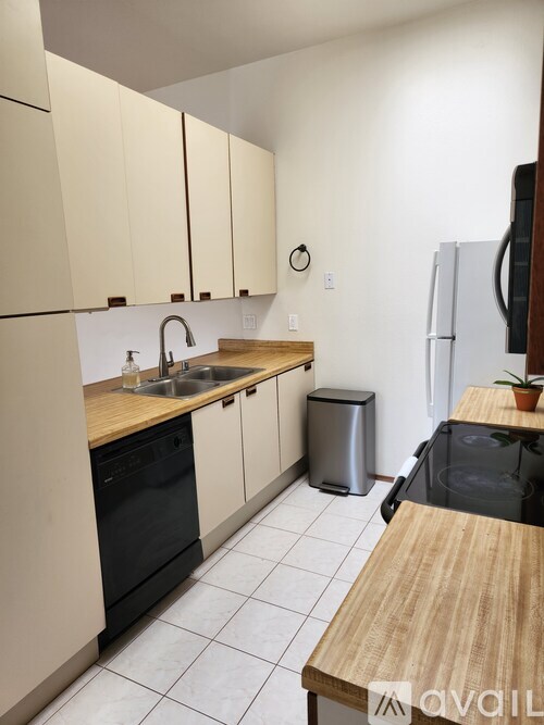 A kitchen with a black dishwasher and a white fridge.