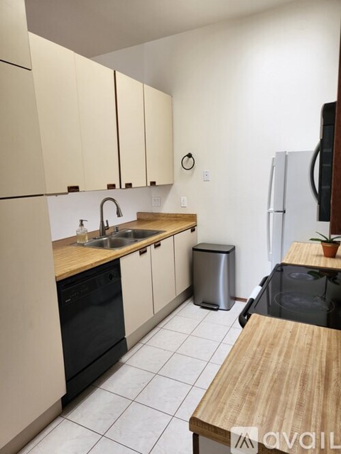 A kitchen with a black dishwasher and a white fridge.