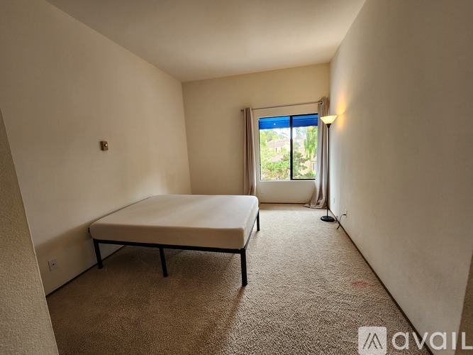 A bedroom with a bed, carpet, and a window.