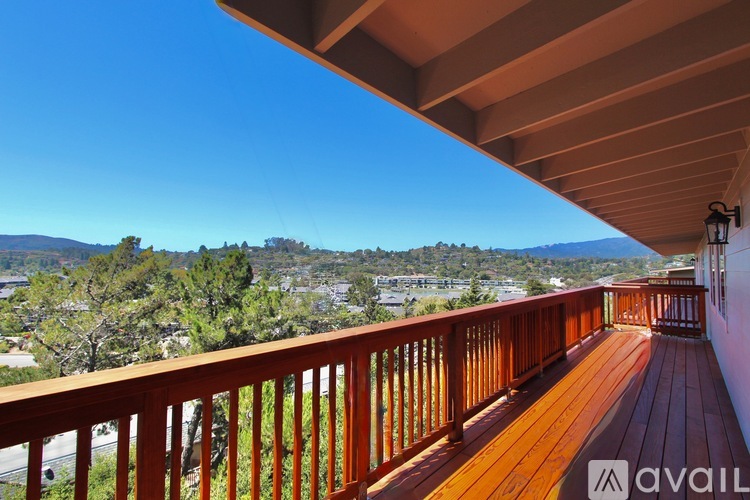 A wooden deck with a view of a town and mountains.