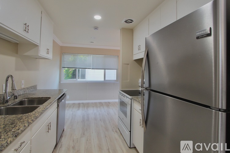 A modern kitchen with a stainless steel refrigerator and a sink with a granite countertop.
