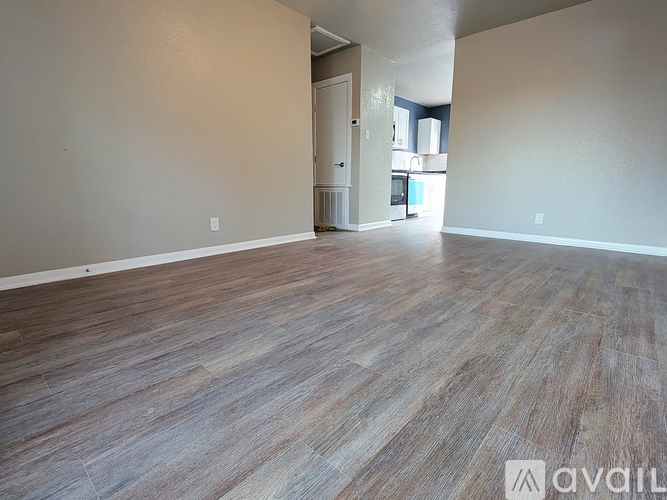 A room with wooden flooring and a doorway leading to another room.
