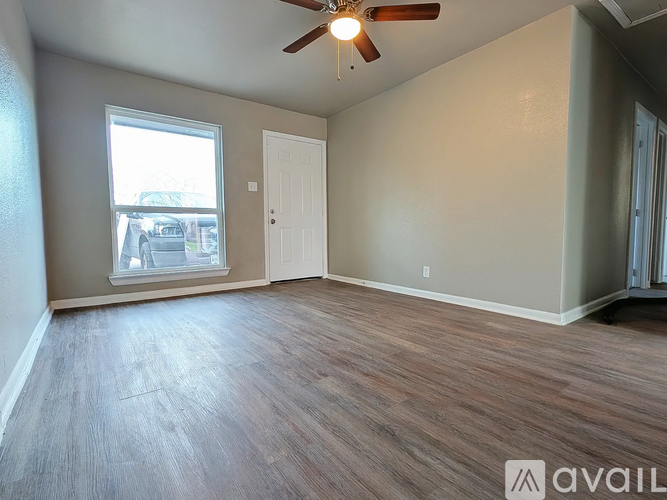 A room with a ceiling fan and a window overlooking a parking lot.