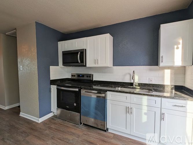 A kitchen with white cabinets and a black microwave.