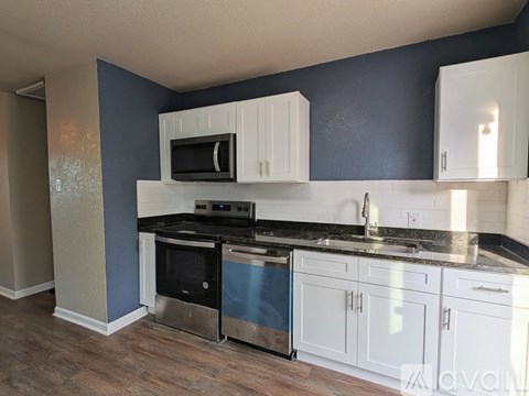 A kitchen with white cabinets and a black microwave.