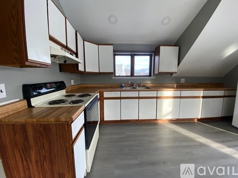 A kitchen with a black stove top oven and wooden cabinets.