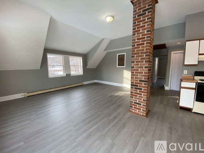 A spacious room with a brick pillar and grey walls.