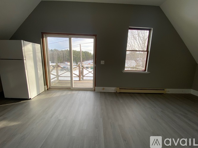 A room with a grey wall and a window with a view of a parking lot.