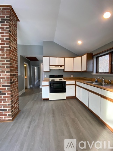 A kitchen with a brick column and white cabinets.
