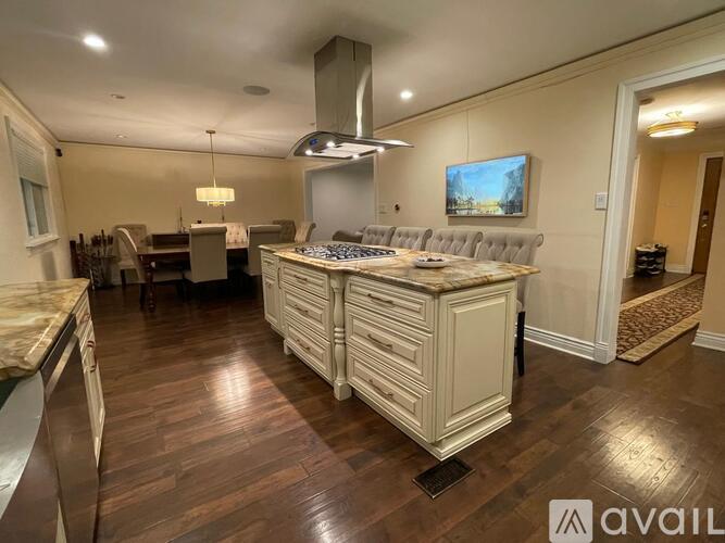 A well-lit kitchen with a large island and a TV mounted on the wall.