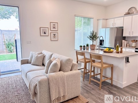 A living room with a couch and a kitchen area in the background.