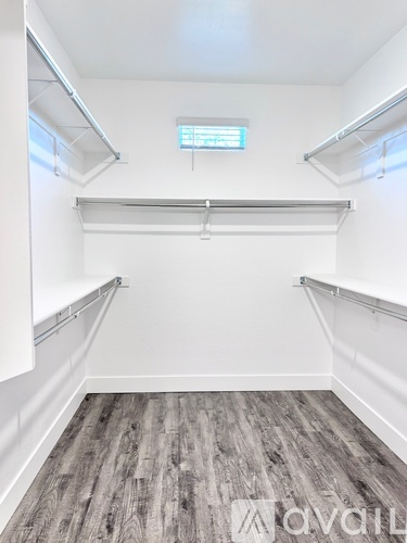 A spacious room with a wooden floor and white walls.