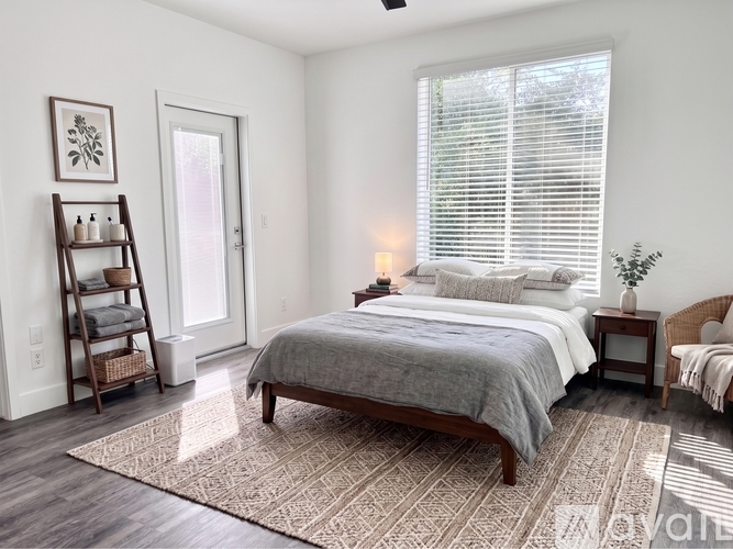 A bedroom with a large bed and a window with blinds.