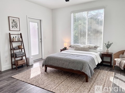 A bedroom with a large bed and a window with blinds.