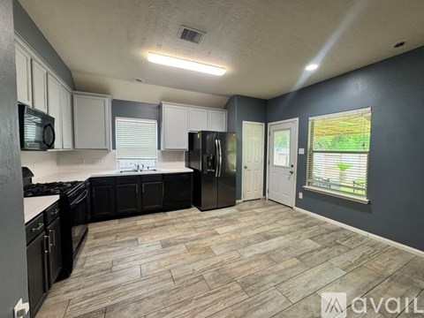 A kitchen with black cabinets and a wooden floor.