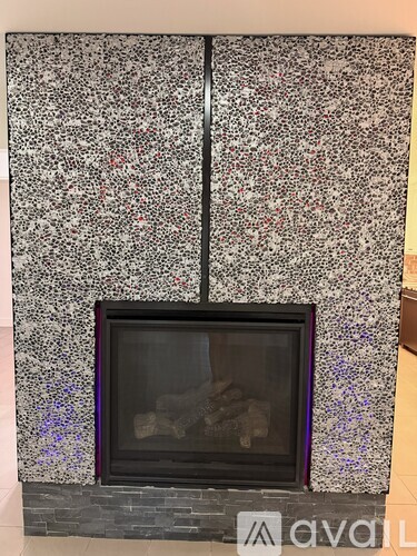 A fireplace with a black frame and a grey and white speckled wall.