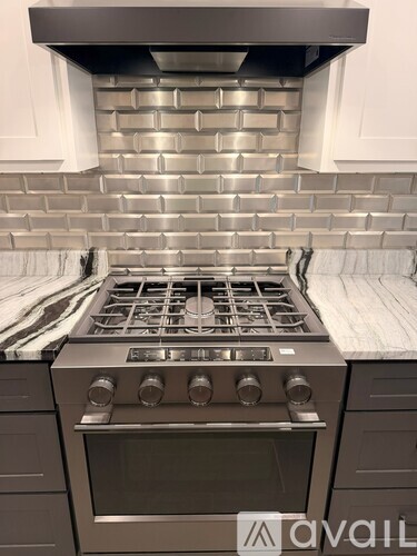 A modern kitchen with a stove top oven and a backsplash of tiles.