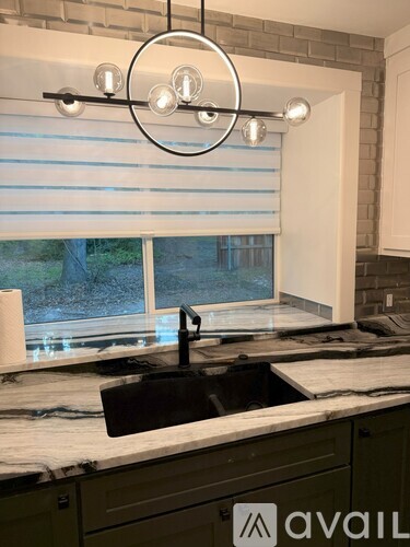 A kitchen with a black sink and a marble countertop.