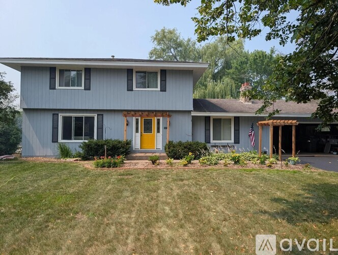A house with a grey exterior and a yellow door is for sale.