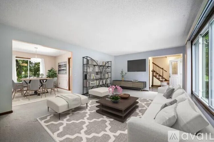 A living room with a white couch, a coffee table, and a dining table with chairs.