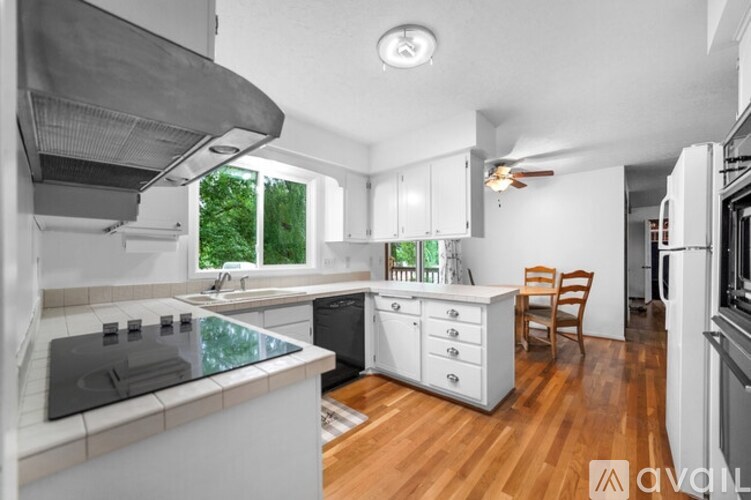 A kitchen with white appliances and wooden floors.