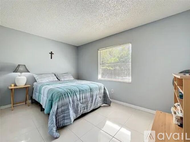 A bedroom with a bed, nightstand, and window.