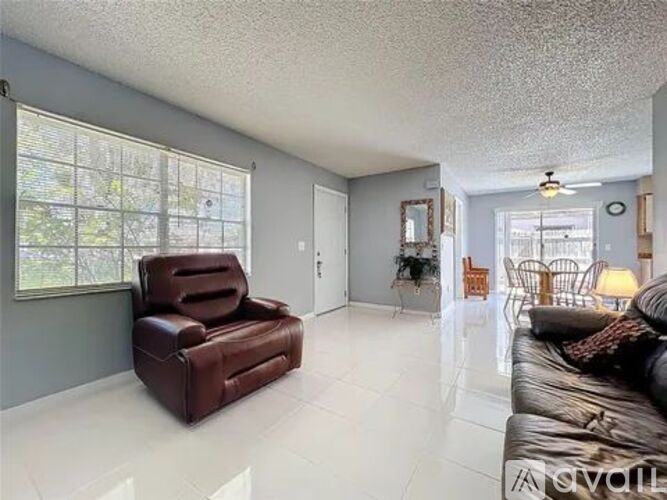 A living room with a brown leather chair and a brown leather couch.