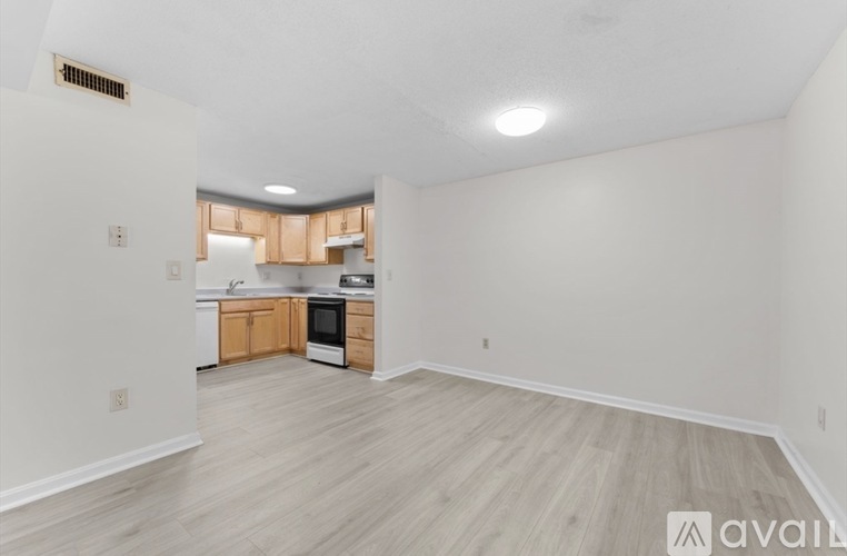 A kitchen with white walls and wooden floors is available for rent.
