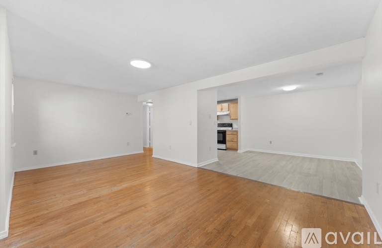 A spacious room with wooden flooring and white walls.