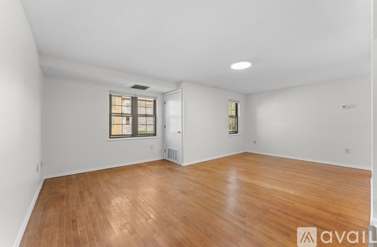 A room with wooden flooring and a window with blinds.