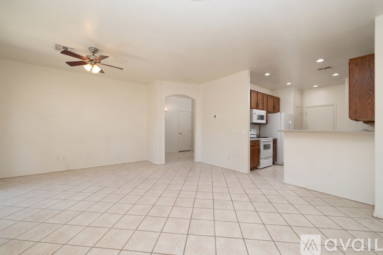 A spacious living room with a ceiling fan and tiled flooring.