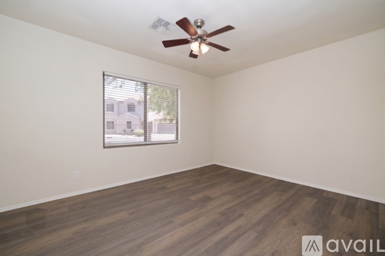A room with a ceiling fan and a window showing a building outside.