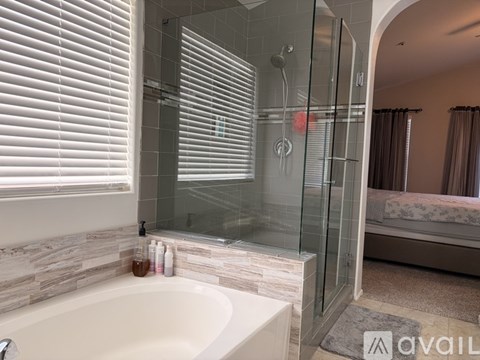 A bathroom with a glass shower door and a stone wall.