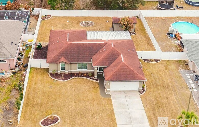 A house with a red roof and a pool in the backyard.
