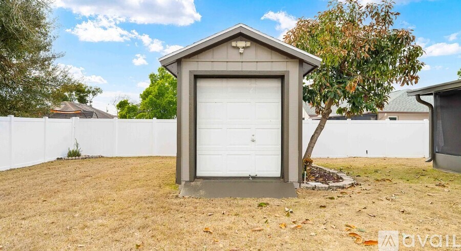 A detached garage with a white door is situated in a grassy area.