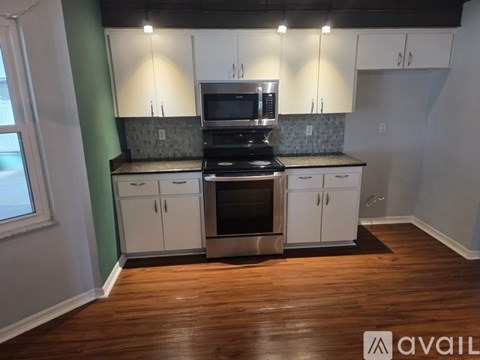 A kitchen with white cabinets and a green wall.