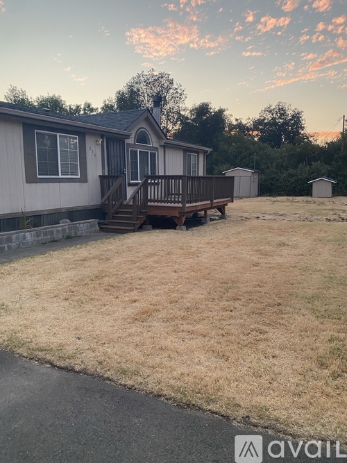 A house with a deck and a small shed in the background.