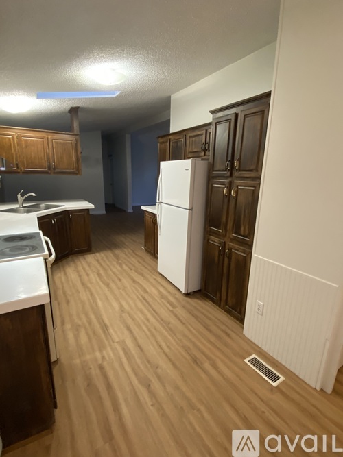 A kitchen with a white fridge and wooden cabinets.