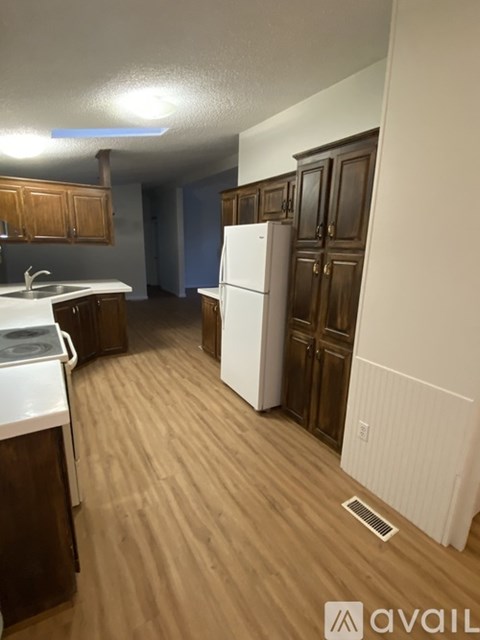 A kitchen with a white fridge and wooden cabinets.
