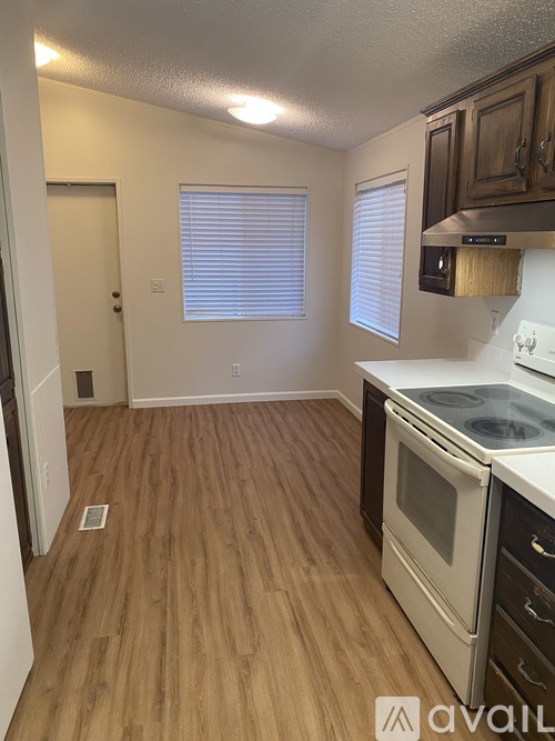 A kitchen with wooden floors and white appliances.