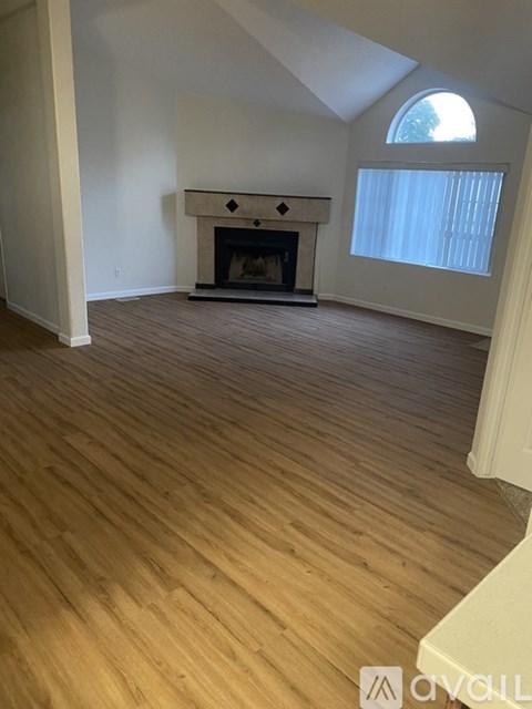 A living room with a fireplace and wood flooring.