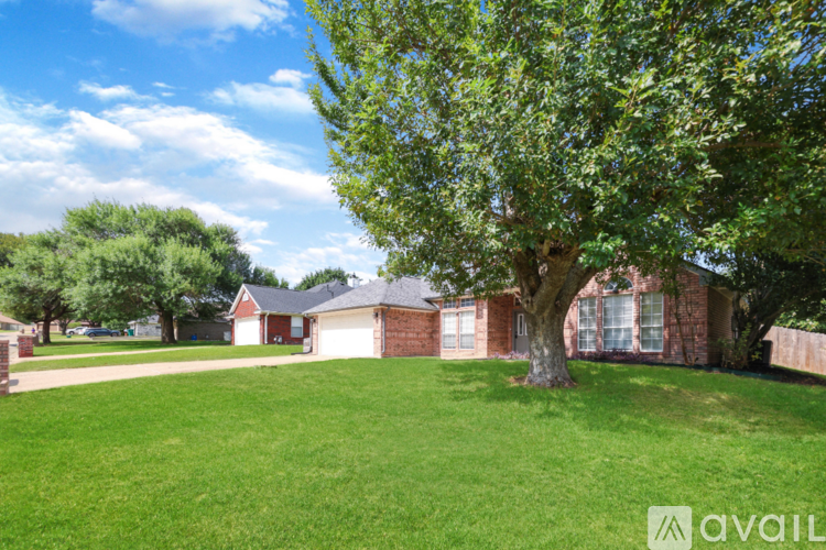 A tree in a yard with a house in the background.