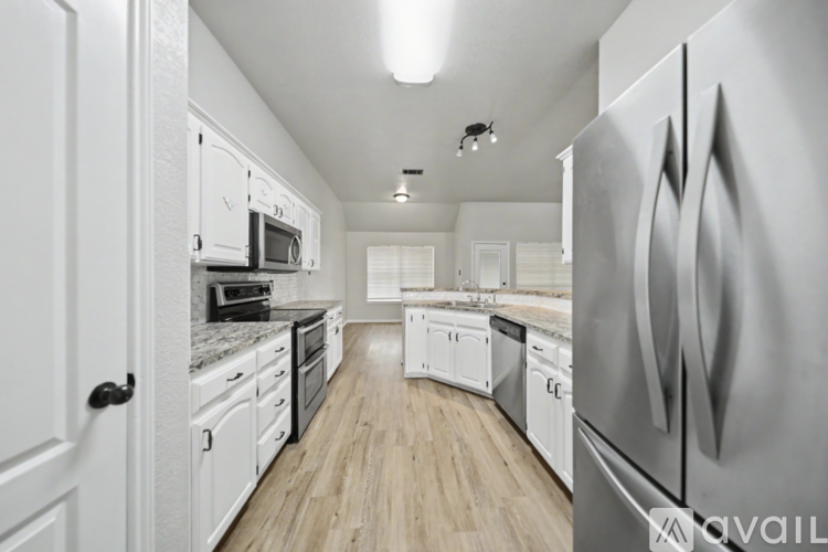 A modern kitchen with white cabinets and stainless steel appliances.
