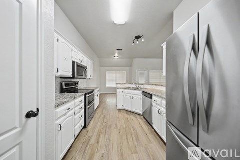 A modern kitchen with white cabinets and stainless steel appliances.