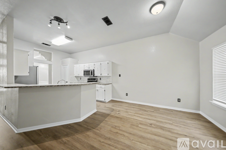 A kitchen with white cabinets and a wooden floor.