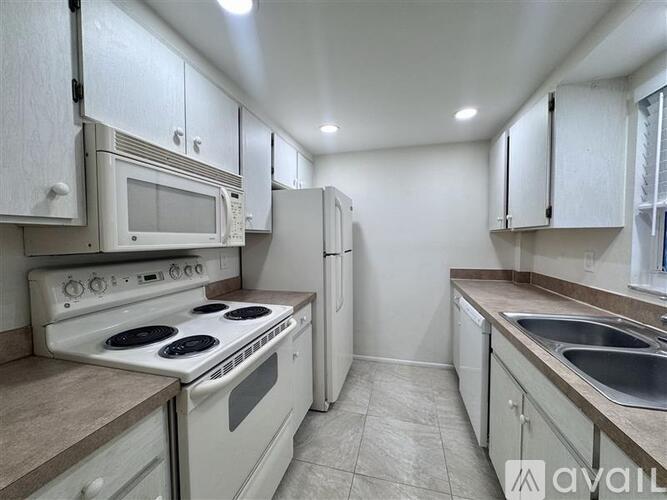 A kitchen with white appliances and cabinets.