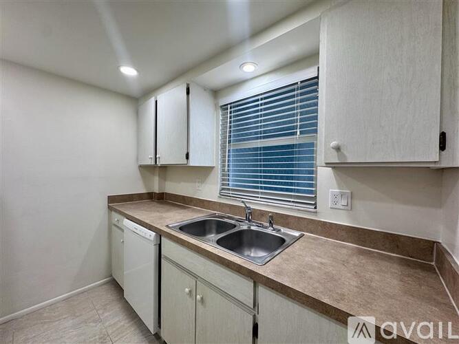 A kitchen with a sink, dishwasher, and cabinets.