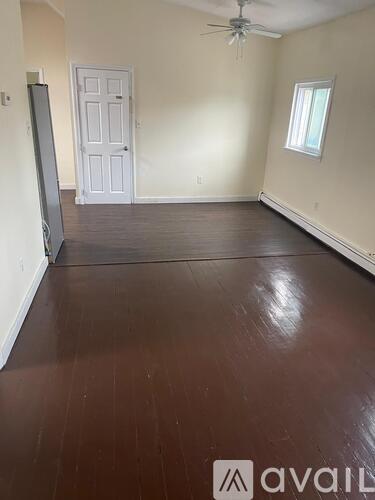 A room with wooden flooring and a ceiling fan.